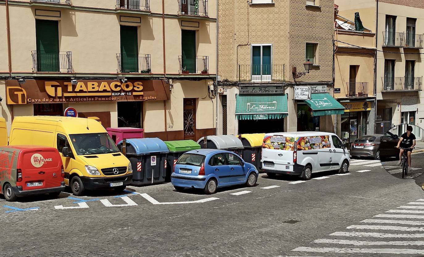 Un ciclista circula por el centro de la calle ante la presencia de dos vehículos en doble fila.