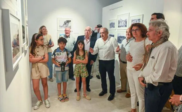 El fotógrafo Fran Jimenez explica a varios de los asistentes (entre ellos, sus tres nietos) la exposición.