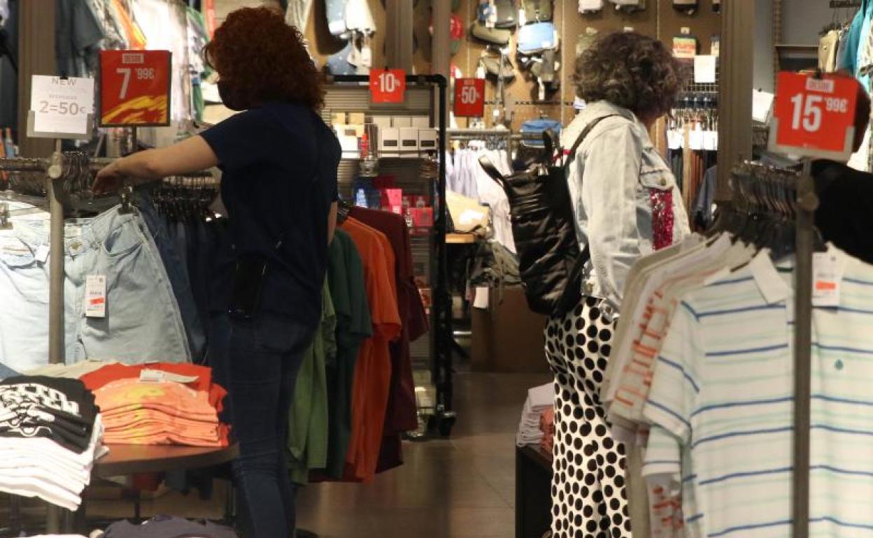 Dos mujeres buscan prendas de rebajas en un comercio.