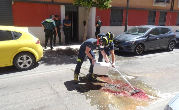 Los Bomberos limpian los restos de sangre a la puerta del bloque donde residía la víctima. 