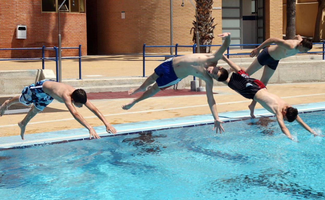 Un grupo de jóvenes se lanzan de cabeza a una piscina. 