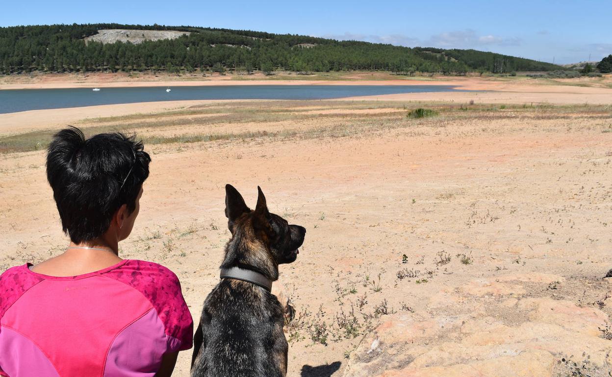 Una vecina y su perra, Kara, observan el embalse de Aguilar de Campoo desde la zona de la playa. 