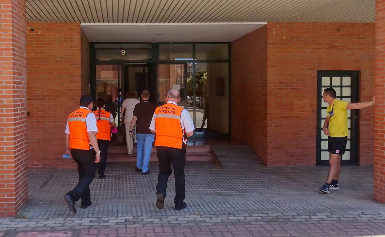 La forense y los empleados del servicio funerario acceden al portal de la plaza de los Ferroviarios. 