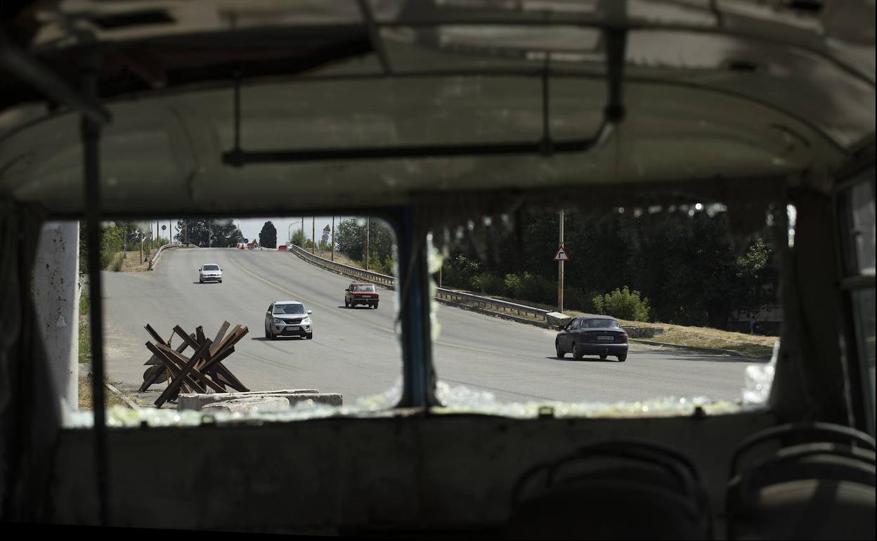 Varios automóviles pasan junto a un autobús destruido en la carretera que conduce a Dnipro (Ucrania).