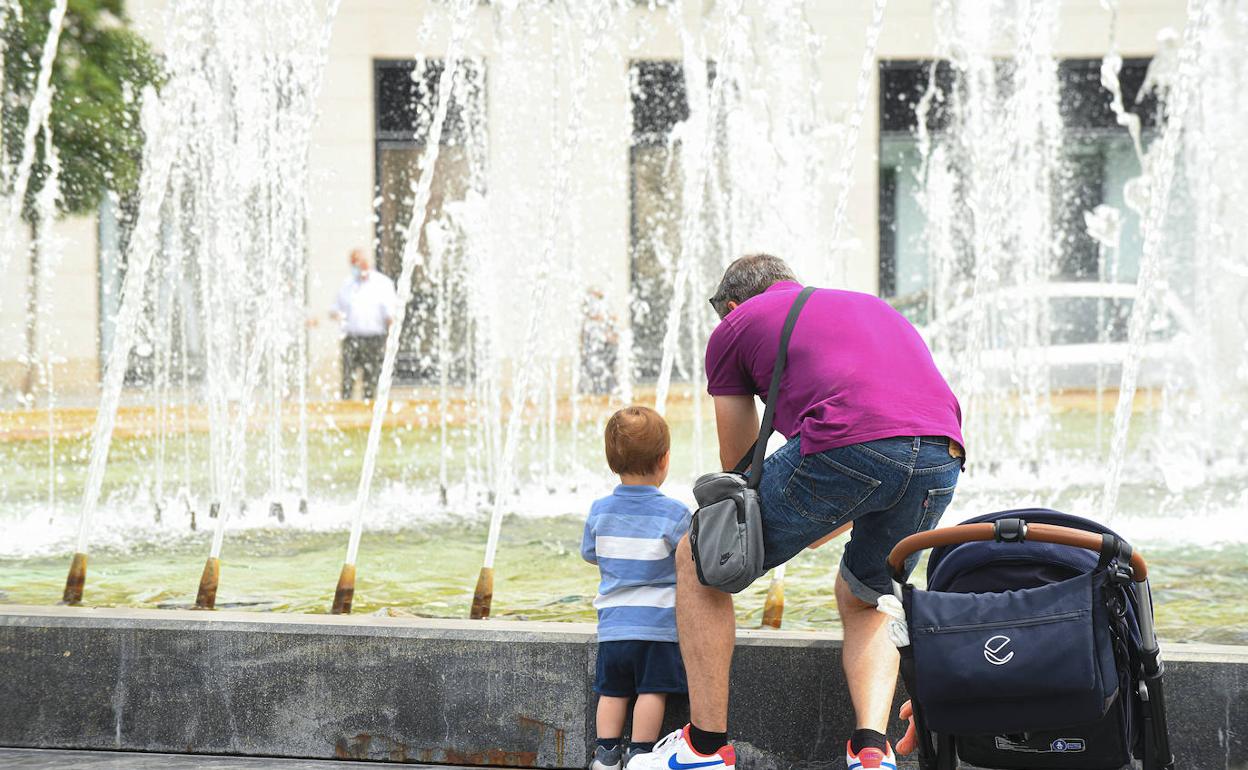 Un padre y su hijo se refrescan ante las altas temperaturas