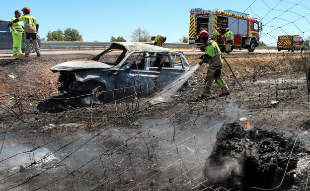 Imagen principal - Los bomberos apagan el coche incendiado. 