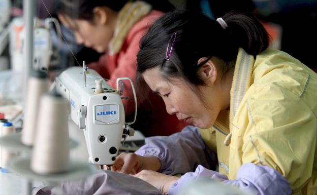 Una trabajadora cose una prenda en una línea de producción en la fábrica de ropa en China. 