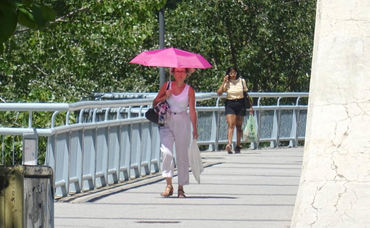 Una mujer se protege del sol por el puente de Hispanoamérica. 