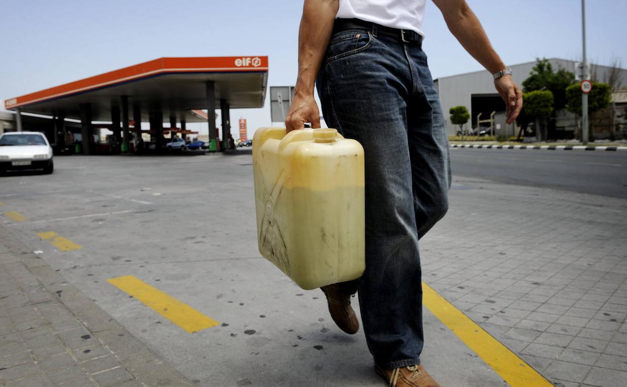 Un hombre lleva una garrafa de carburante, que ha llenado en una gasolinera.