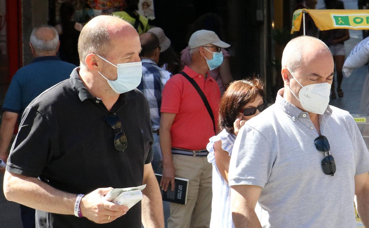 Dos hombres pasean con la mascarilla puesta. 