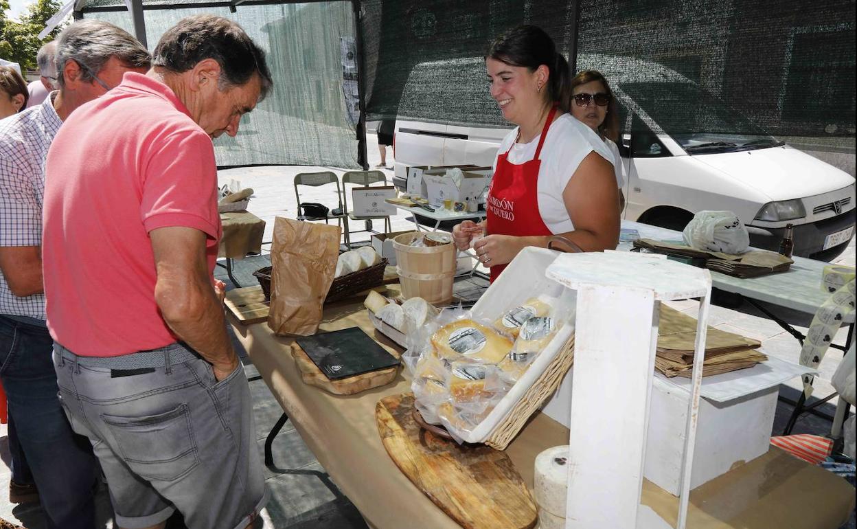 Visitantes se interesan por los quesos de uno de los puestos de la feria. 