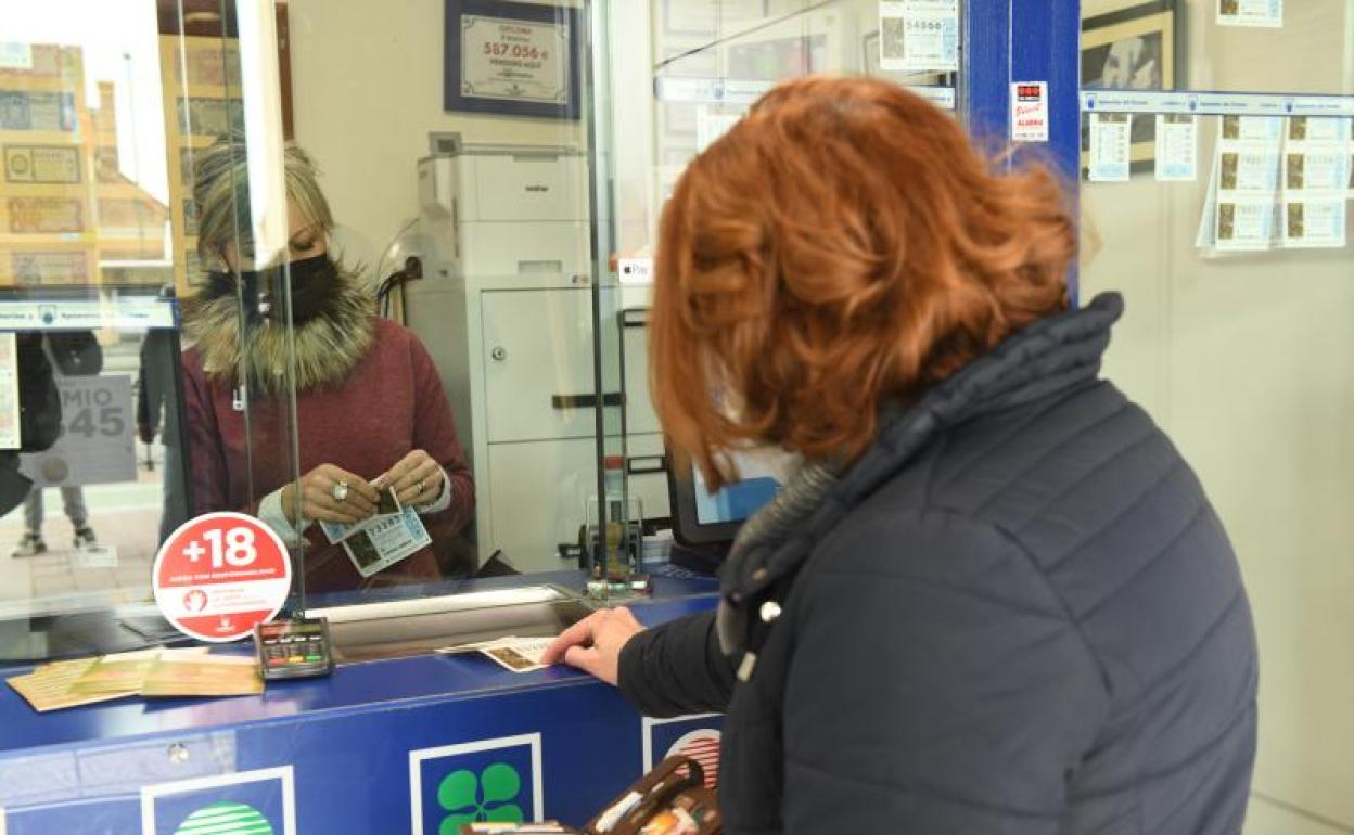 Una mujer compra un boleto en una administración de lotería. 