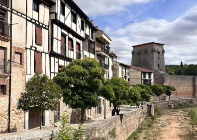 Imagen secundaria 1 - Arriba, Mari Carmen Subiñas, responsable de cocina del restaurante Tiky, de Covarrubias, posa con una olla podrida. Abajo, las casas típicas del municipio y la Colegiata de San Cosme y San Damián. 