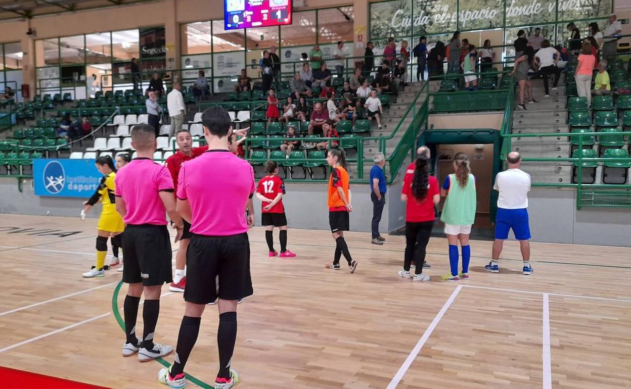 Árbitros, jugadoras y cuerpos técnicos de ambos equipos miran hacia la grada donde atienden a la mujer que ha sufrido un desvanecimiento.