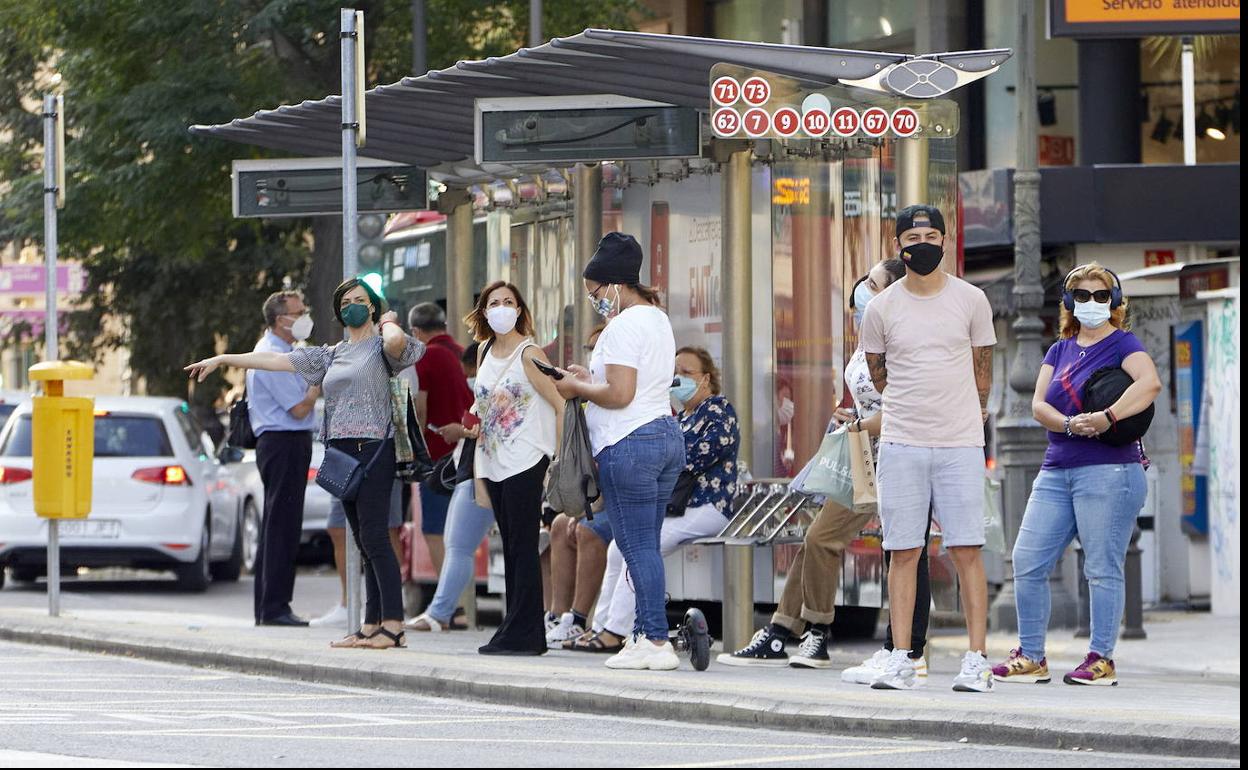 Parada de autobús con los usuarios con la mascarilla puesta. 