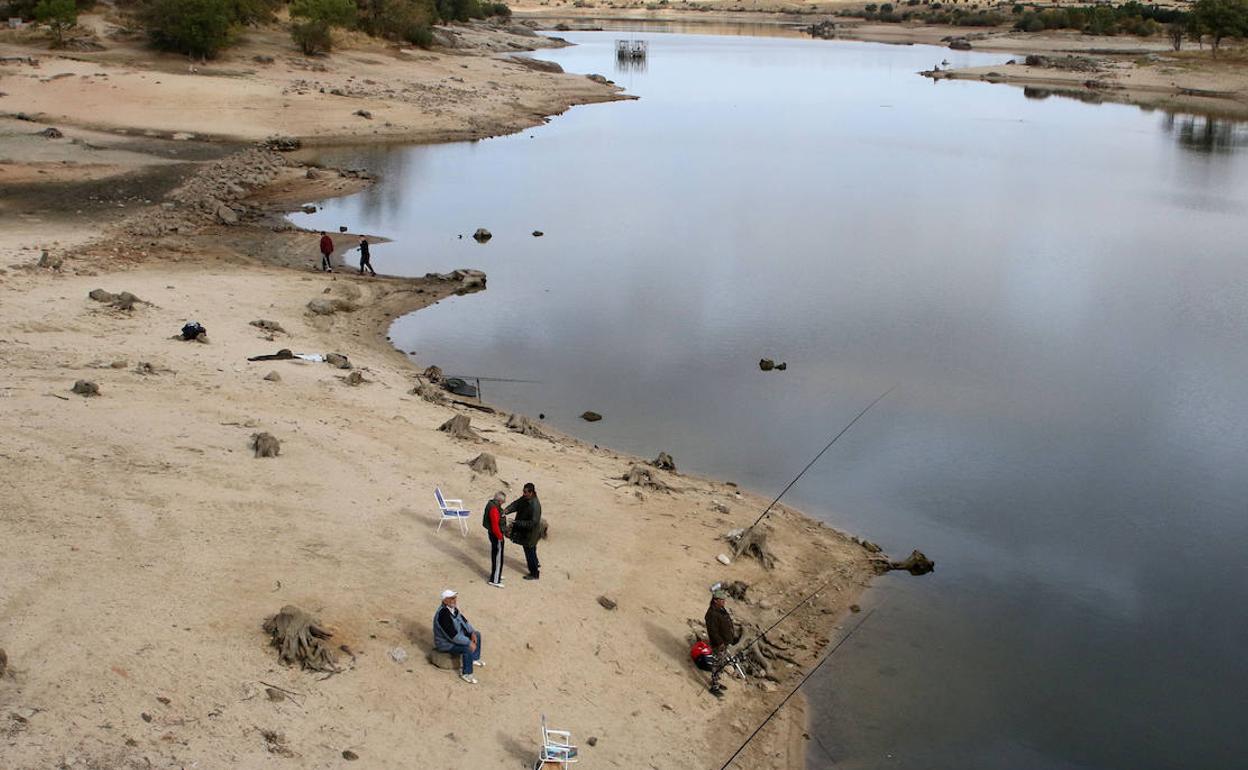 Pescadores en una orilla del Pontón Alto, que deja ver unos márgenes que otrora cubría el agua. 