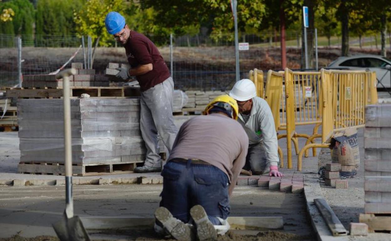 Tres personas trabajan en una obra de ampliación de aceras.