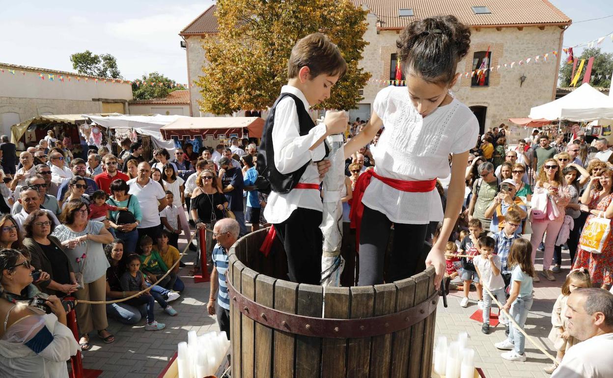 Dos niños pisan la uva para extraer el mosto en la plaza de Quintanilla. 