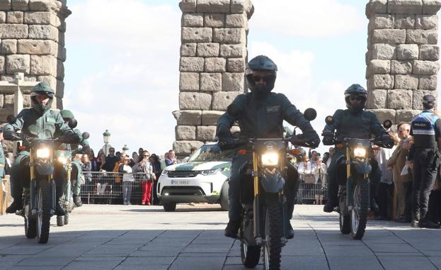 Imagen principal - Arriba, unidades motorizadas en el desfile de este miércoles,. Abajo, a la izquierda, izado de la bandera al inicio del acto, a la derecha, entrega del reconocimiento de Amigo de la Guardia Civil al coronel jefe de la Base Mixta. 