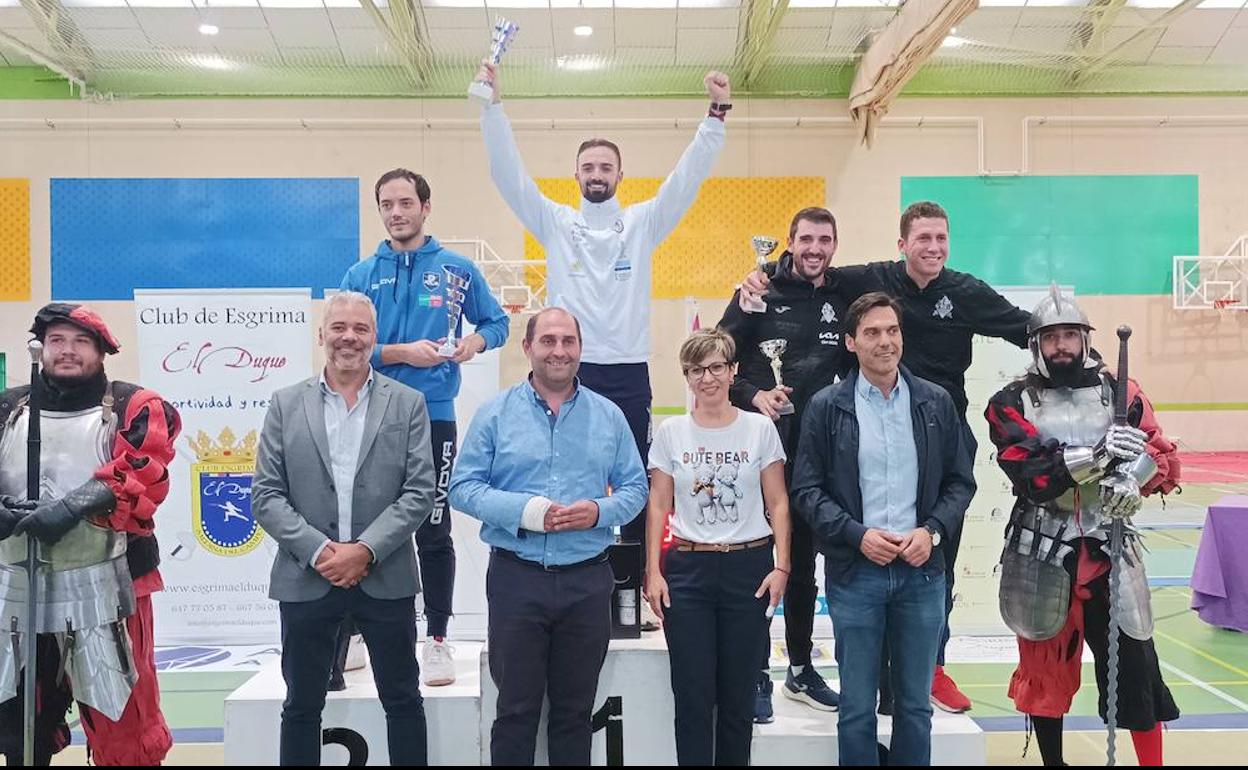 Podio del Torneo de Esgrima con el burgalés Álvaro Ibáñez alzando la copa como vencedor. Raúl Sarrio en segunda posición y compartiendo tercer puesto los tarraconenses Ángel Fabregat y Eugenio Elías. Acompañan en el podio autoridades y dos personas con la vestimenta propia del esgrima histórico