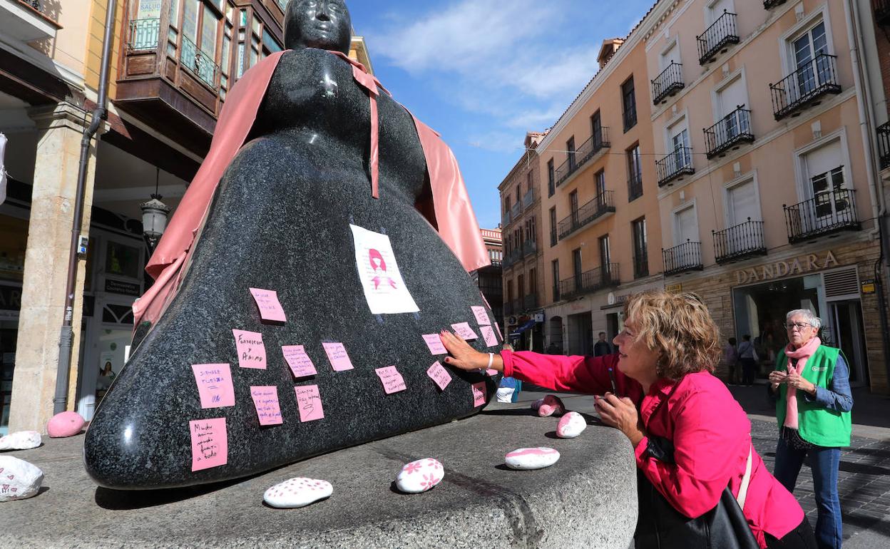 Una mujer coloca un mensaje en el monumento, en la conmemoración del Día del Cáncer de Mama. 