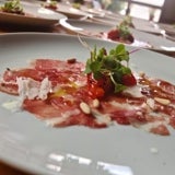 Carpaccio de presa ibérica con pimientos asados y piñón nacional.