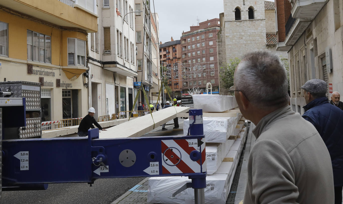 Una grúa de grandes dimensiones trabaja en la calle Burgos para colocar decenas de vigas de madera de tamaño gigante.