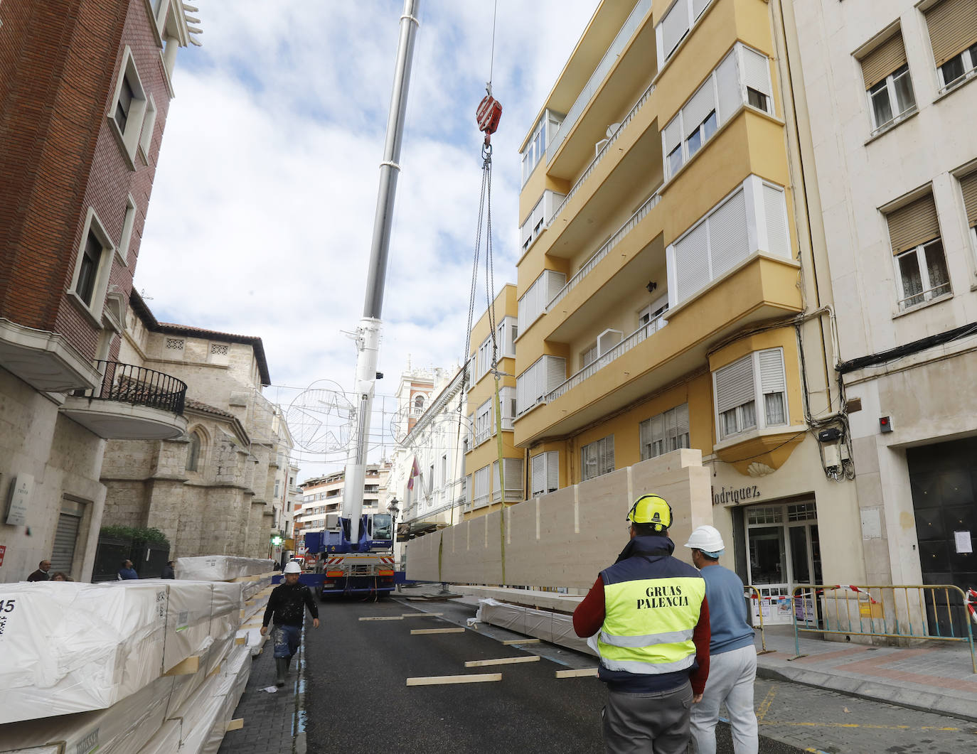 Una grúa de grandes dimensiones trabaja en la calle Burgos para colocar decenas de vigas de madera de tamaño gigante.