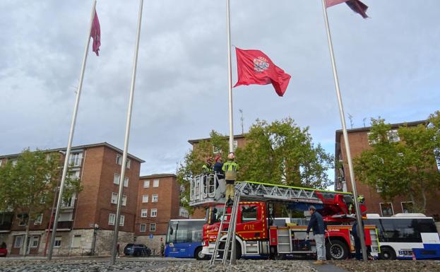 Bomberos y operarios izan la bandera (recién sustituida) de Salamanca en la glorieta de la Comunidad. 