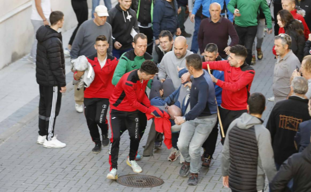 Varios aficionados taurinos trasladan al herido para llevarlo hasta la ambulancia. 