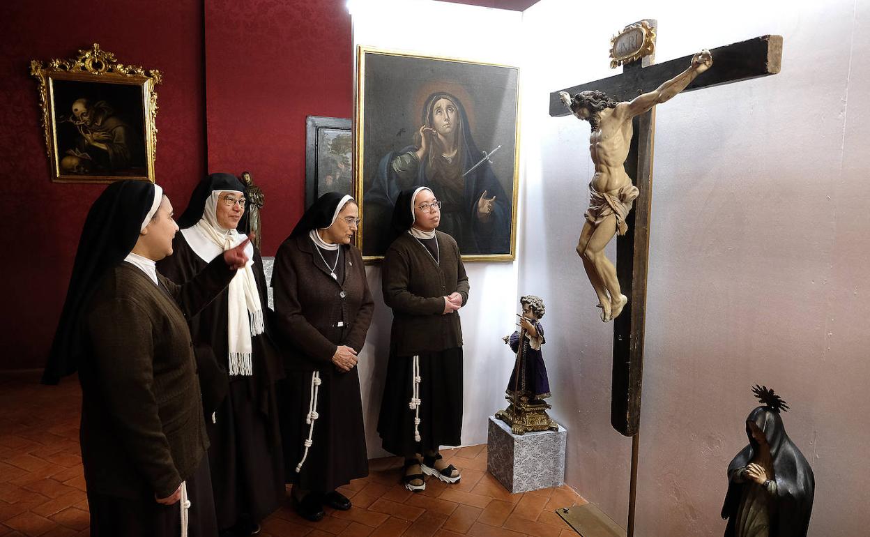 Cuatro monjas clarisas contemplan un Cristo de la exposición que se inauguró este jueves en su convento. 