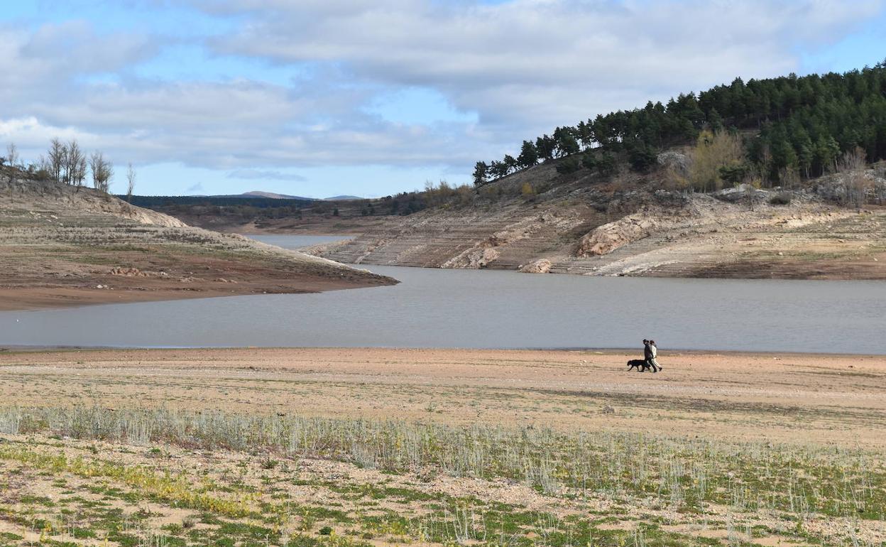 Dos paseantes y un perro pasean por el lecho del embalse de Aguilar de Campoo a primeros de este mes. 