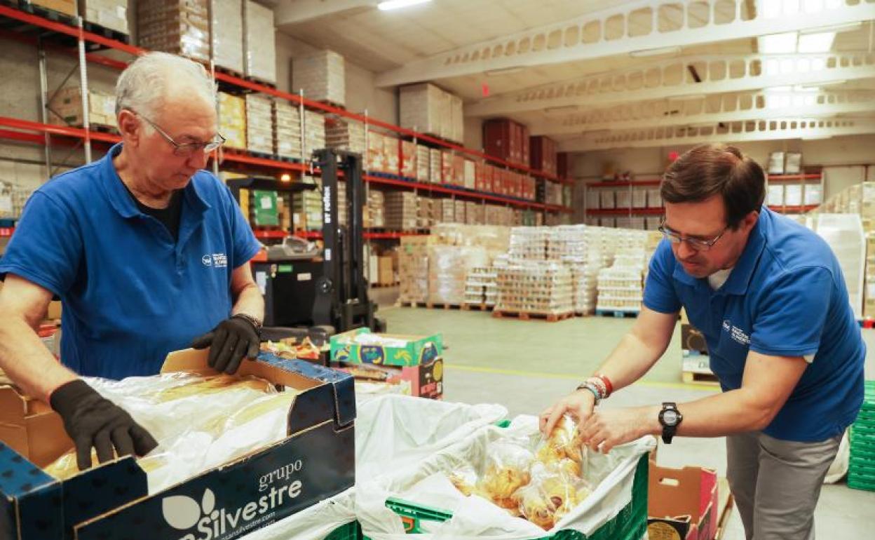 Dos voluntarios clasifican los alimentos que reciben en las instalaciones del Banco de Alimentos. 