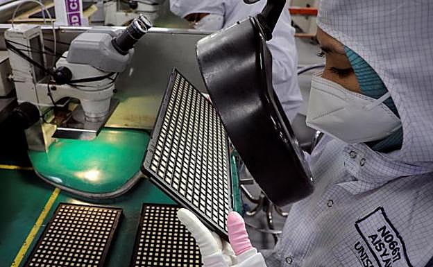 Una operaria revisa una placa de semiconductores en una planta de Malasia. 