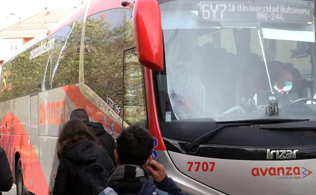 Pasajeros que viajan a Madrid hacen cola para subir a un autobús en Segovia. 