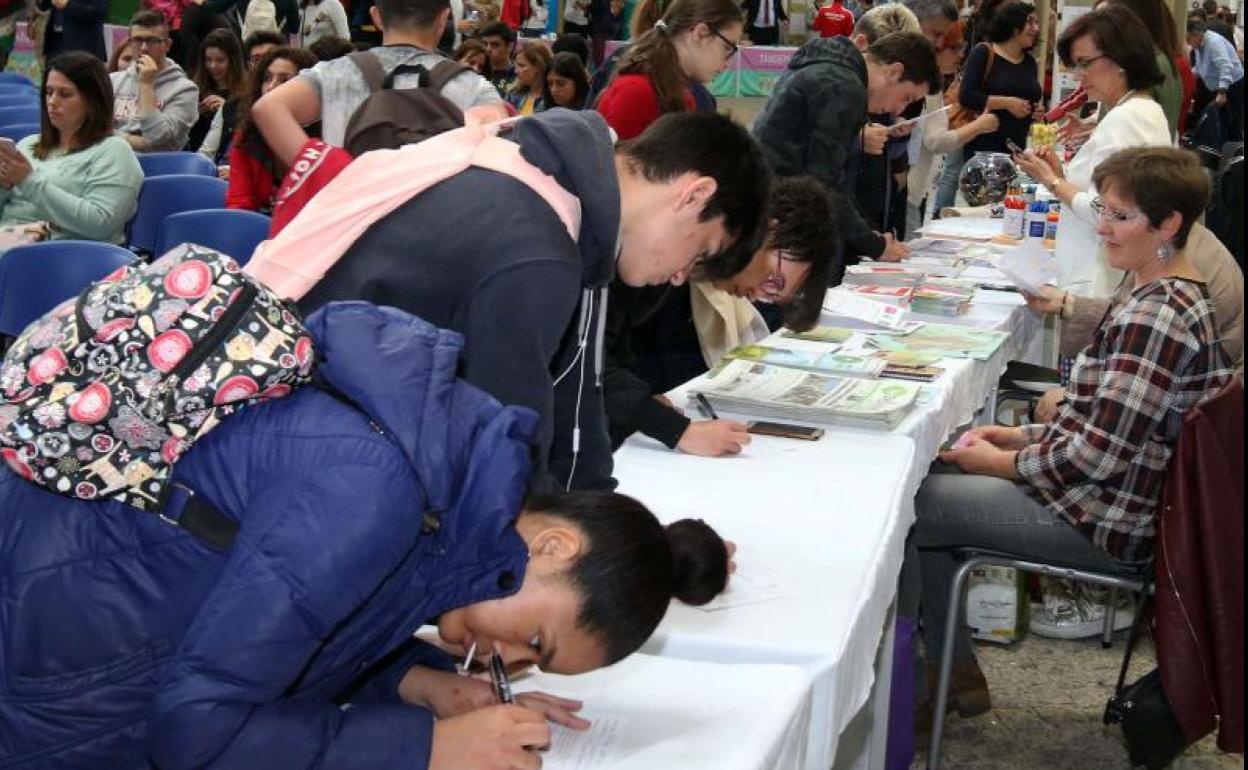 Jóvenes se apuntan a ofertas laborales en una feria de empleo en Segovia. 