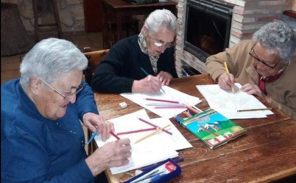 Tres mujeres participan en un taller de estimulación cognitiva en Saldaña de Ayllón. 