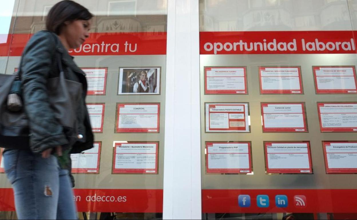 Una joven pasa ante un escaparate con ofertas de empleo. 