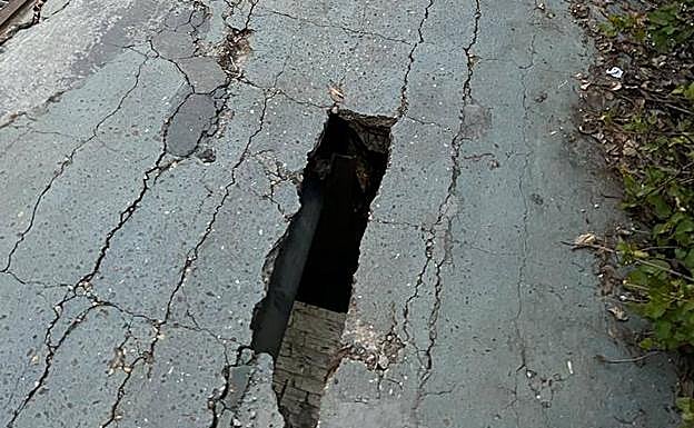 El agujero en la acera con el pavimento de alrededor agrietado. 
