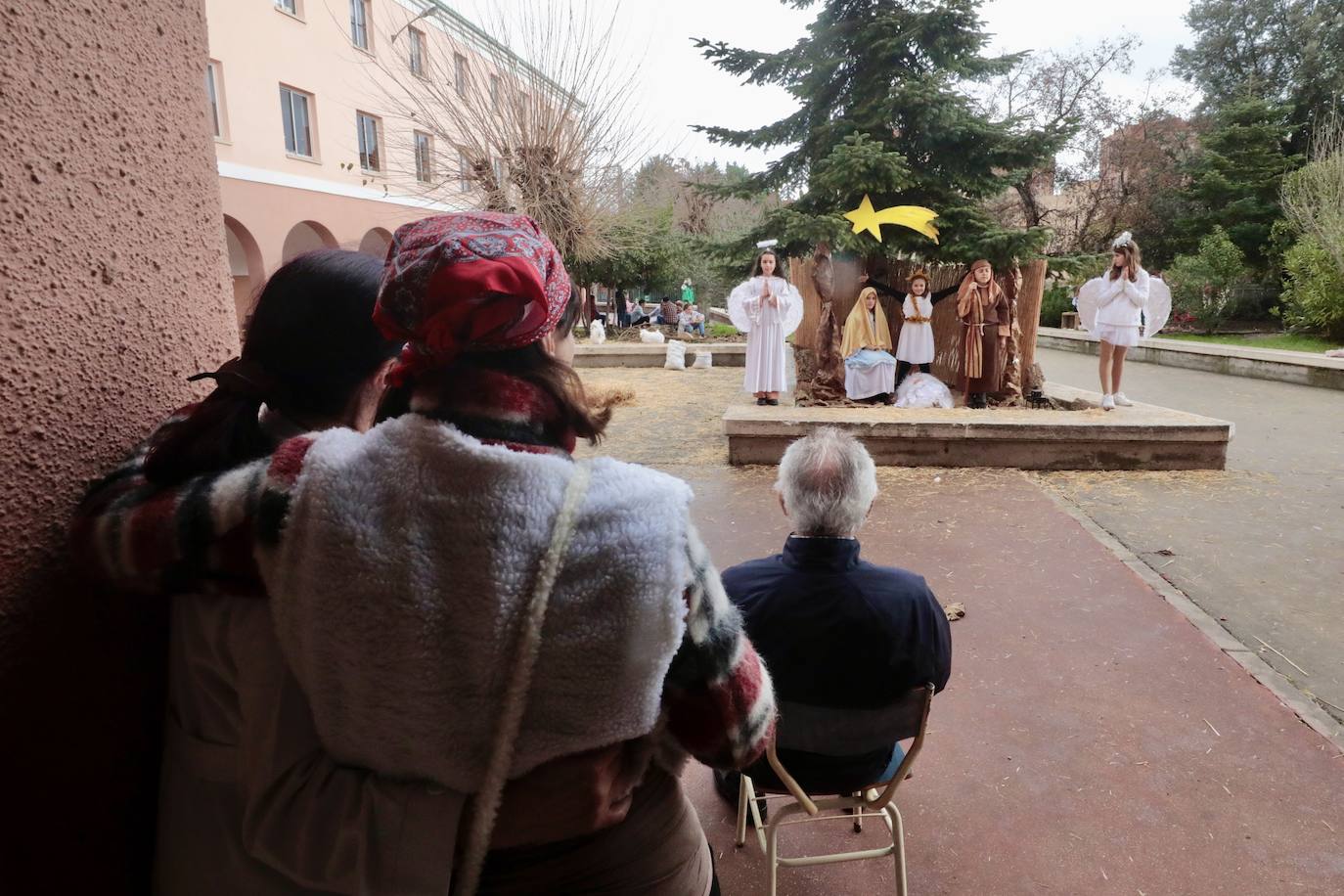 Ancianos observan a los alumnos interpretar el belén viviente.