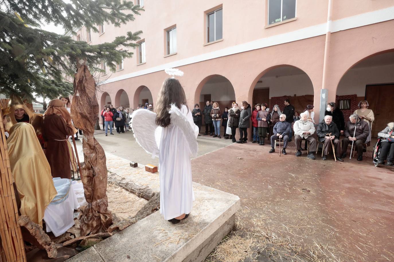 Ancianos observan a los alumnos interpretar el belén viviente.