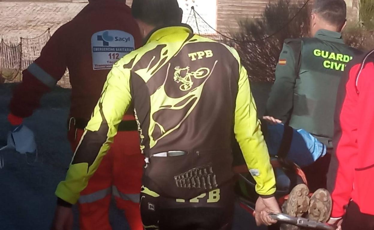 Emergencias sanitarias, compañeros del herido y la Guardia Civil trasladan en camilla al herido en La Pinilla. 