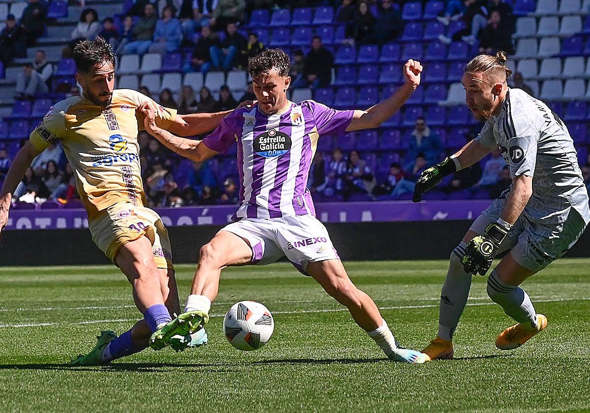 Un futbolista del Palencia intenta batir al meta del Real Valladolid Promesas.