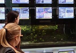 Dos mujeres miran un escaparate con ofertas de viviendas en Segovia.