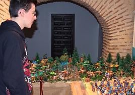 Un joven observa la exposición de Playmobil ambientada en el salvaje oeste.