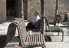 Una vecina mayor de Fermoselle, en Zamora, descansa en los bancos de una plaza.