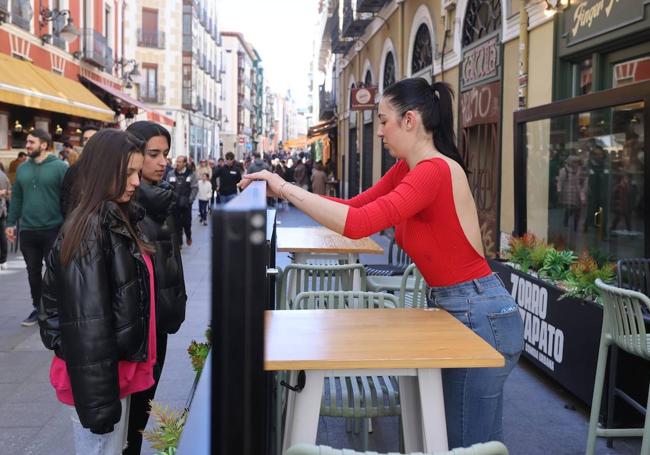 Lucía Fernández coloca el biombo que delimita el espacio de la terraza con la calle.