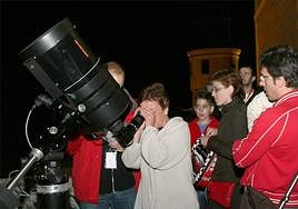 Una mujer mira por un telescopio en una actividad de observación astronómica.