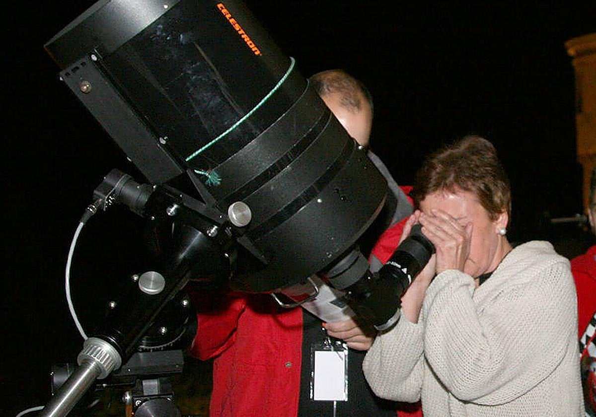 Una mujer mira por un telescopio en una actividad de observación astronómica.