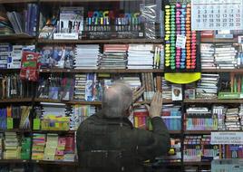 Un lector busca un título en la estantería de una librería.